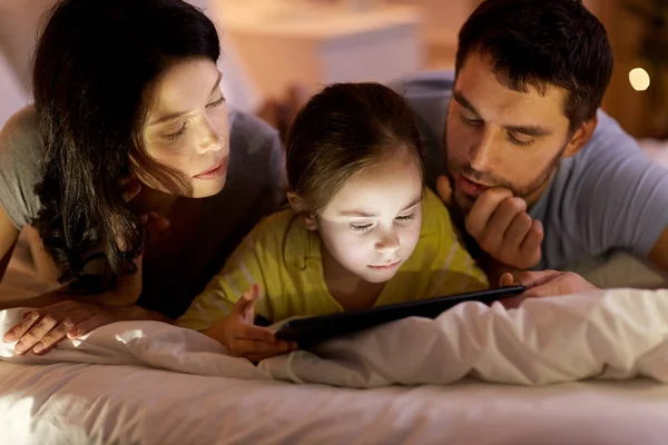 Familj med TabletPC i sängen på natten hemma — Stockfoto