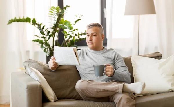 Hombre leyendo el periódico y tomando café en casa — Foto de Stock