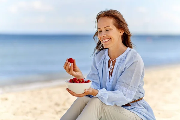 Donna felice mangiare fragole sulla spiaggia estiva — Foto Stock