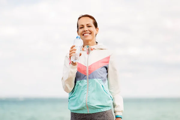 Kvinna dricksvatten efter träningen på seaside — Stockfoto