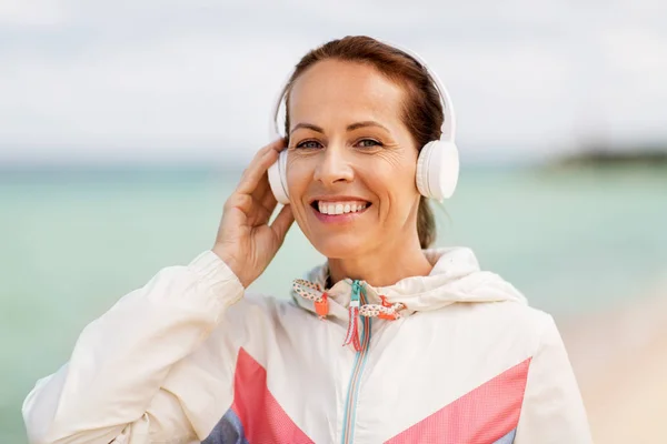 Woman with headphones listening to music on beach — Stock Photo, Image