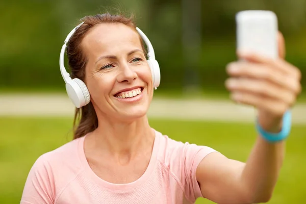 Mulher em telefones leva selfie por smartphone no parque — Fotografia de Stock