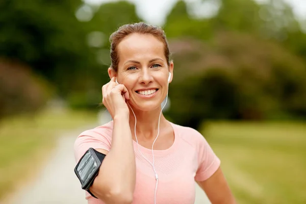 Vrouw met koptelefoon luisteren naar muziek in het park — Stockfoto