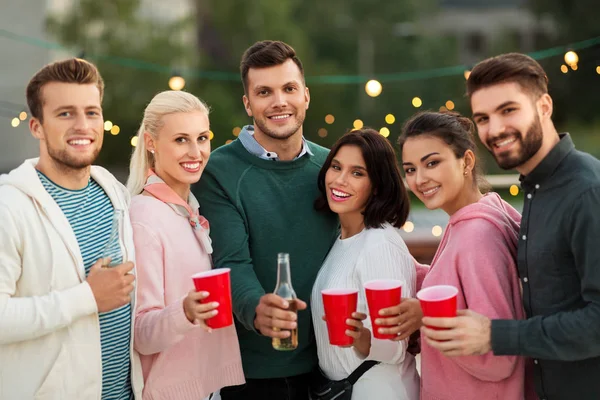 Vrienden met dranken in partij kopjes bij dak — Stockfoto