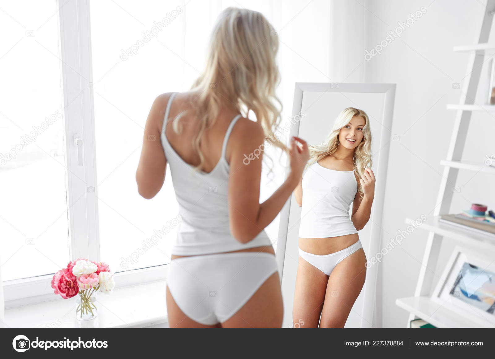 Woman in underwear looking at mirror in morning Stock Photo by