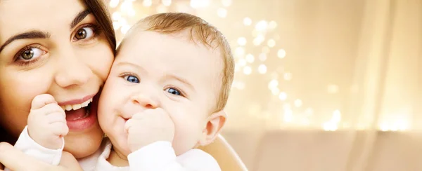 Close up de mãe com bebê sobre luzes de Natal — Fotografia de Stock