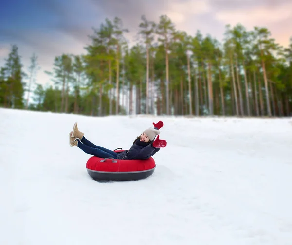 Счастливая девочка-подросток скользит с холма по снежной трубе — стоковое фото