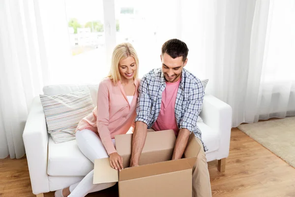Casal feliz com caixa de pacote aberto em casa — Fotografia de Stock