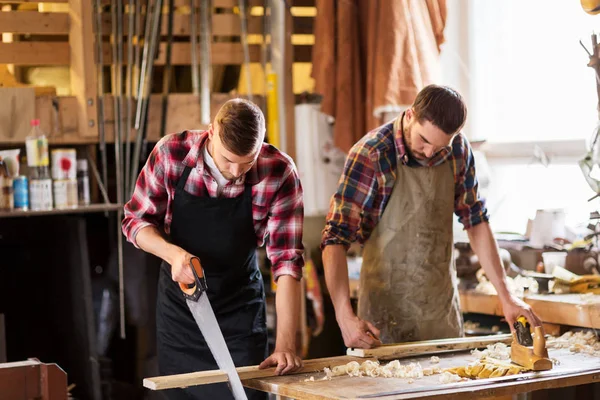 Falegnami che lavorano con sega e legno in officina — Foto Stock