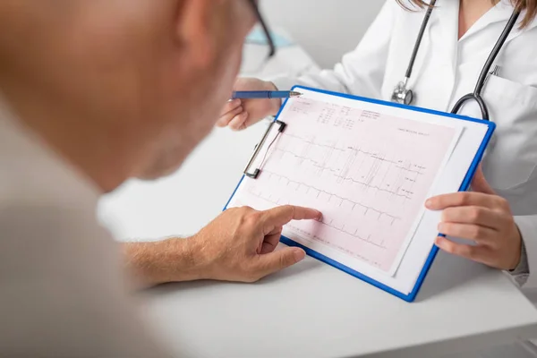 Homem idoso e médico com cardiograma no hospital — Fotografia de Stock