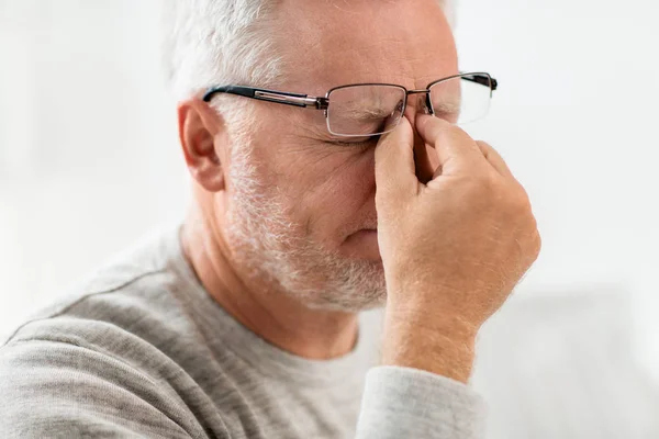 Senior man in glazen brug van de neus te masseren — Stockfoto