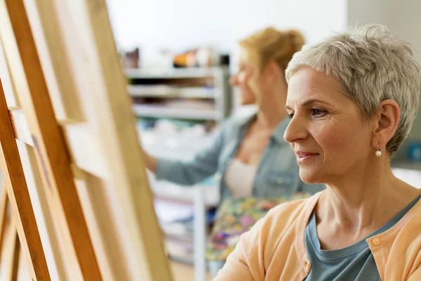 Seniorin zeichnet auf Staffelei im Atelier der Kunstschule — Stockfoto