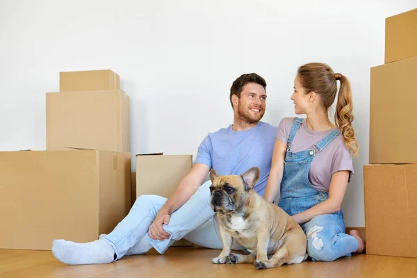 Happy couple with boxes and dog moving to new home — Stock Photo, Image