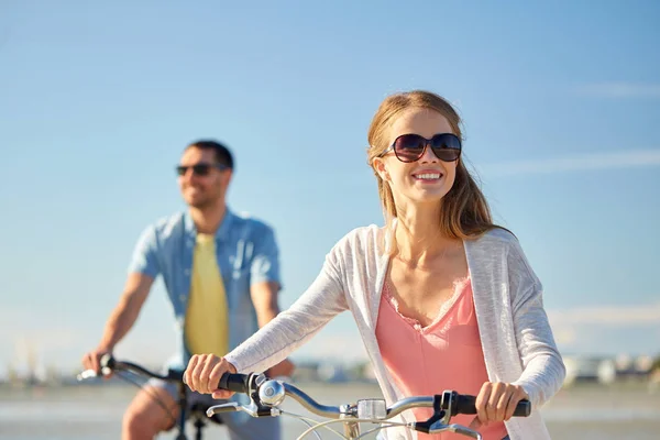 Счастливая молодая пара на велосипедах на берегу моря — стоковое фото
