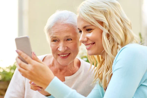 Hija y madre mayor con teléfono inteligente al aire libre — Foto de Stock