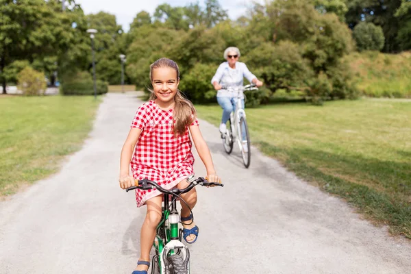 Babička a vnučka, jízda na kole v parku — Stock fotografie
