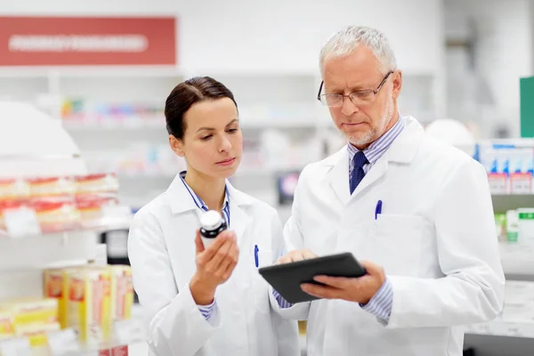 Boticarios con la tableta PC y el medicamento en la farmacia — Foto de Stock