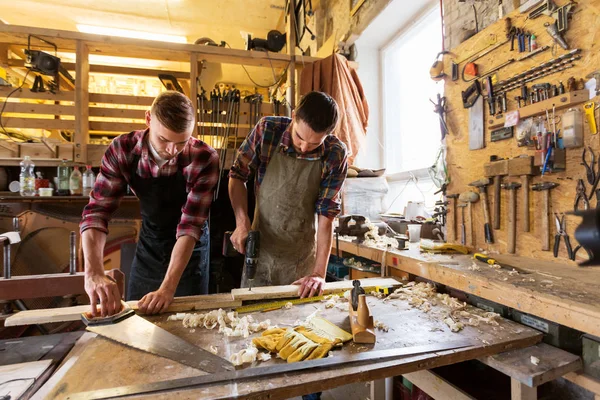 Плотники, работающие с деревянной доской в мастерской — стоковое фото