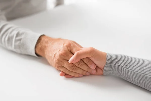 Nahaufnahme einer jungen Frau, die einen älteren Mann an der Hand hält — Stockfoto