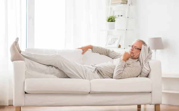 Aîné couché sur le canapé et pensant à la maison — Photo