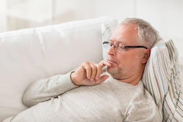 Hombre mayor acostado en el sofá y pensando en casa —  Fotos de Stock