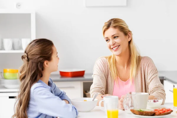 Mãe e filha felizes tomando café da manhã em casa — Fotografia de Stock