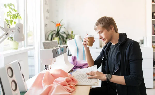 Designer de moda com café e livro no estúdio — Fotografia de Stock