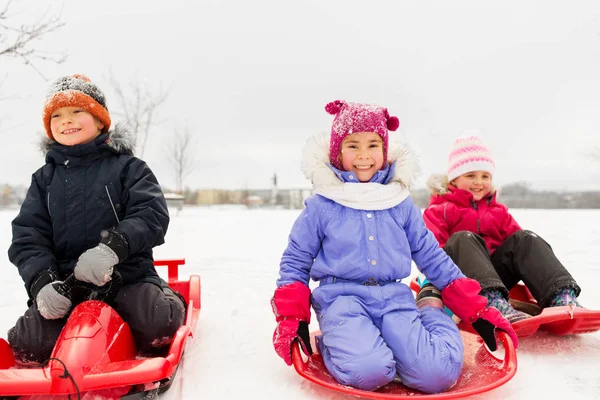 Niños pequeños felices deslizándose hacia abajo en trineos en invierno —  Fotos de Stock