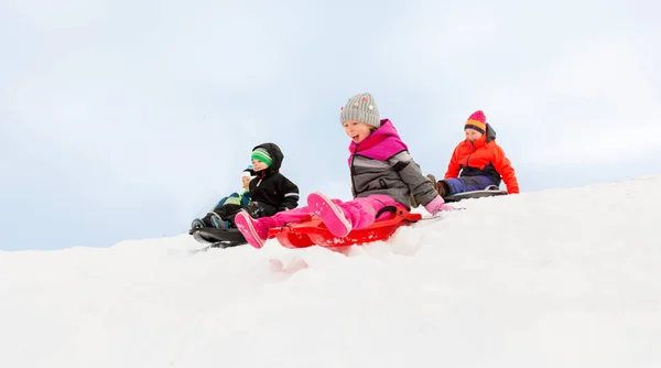 Barn glider på slädarna ner snö backen i vinter — Stockfoto