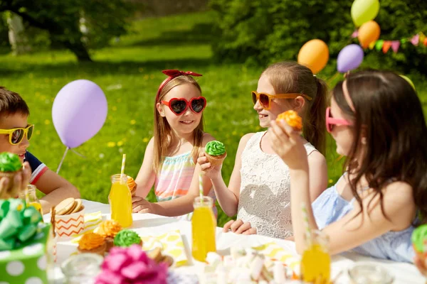 Kids eating cupcakes on birthday party in summer — Stock Photo, Image