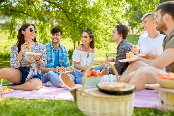 Amici felici mangiare panini al picnic estivo — Foto Stock