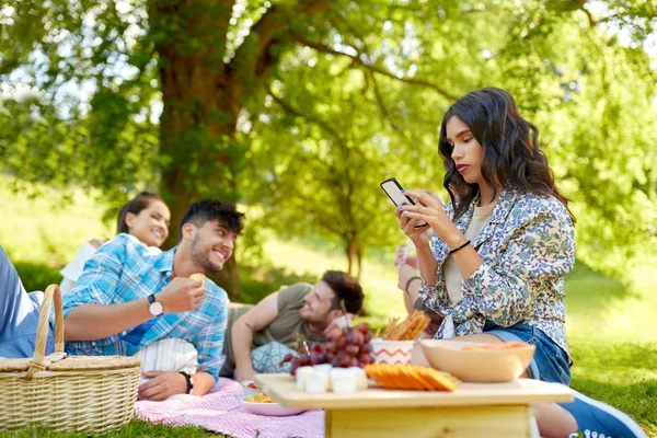 Donna utilizzando smartphone al picnic con gli amici — Foto Stock