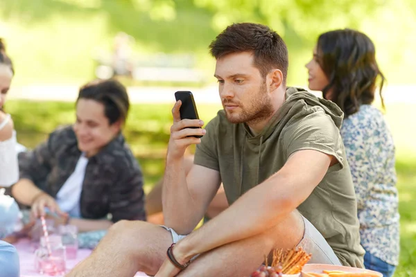 Homem usando smartphone no piquenique com amigos — Fotografia de Stock