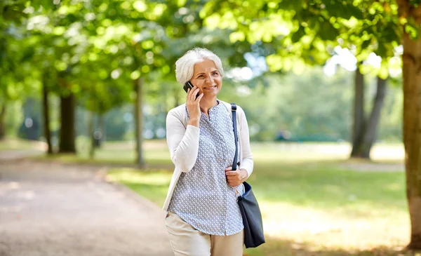 Пожилая женщина звонит на смартфон в летнем парке — стоковое фото