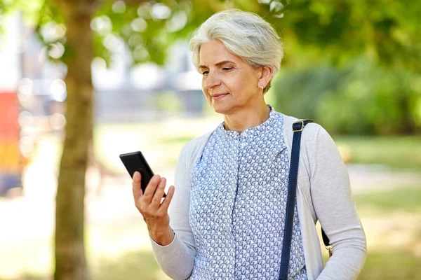 Ευτυχής ανώτερος γυναίκα με smartphone στο πάρκο καλοκαίρι — Φωτογραφία Αρχείου