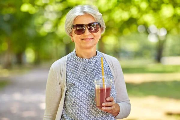 Senior vrouw drinken afhaalmaaltijden schudden bij park — Stockfoto