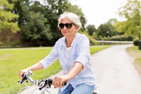 Gelukkig senior vrouw fietsten in zomer park — Stockfoto