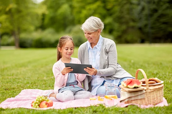 Mormor och barnbarn med tablett på park — Stockfoto
