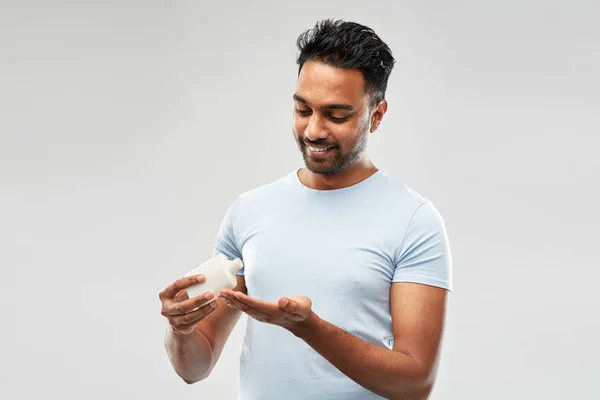 Homem indiano feliz aplicando loção em sua mão — Fotografia de Stock