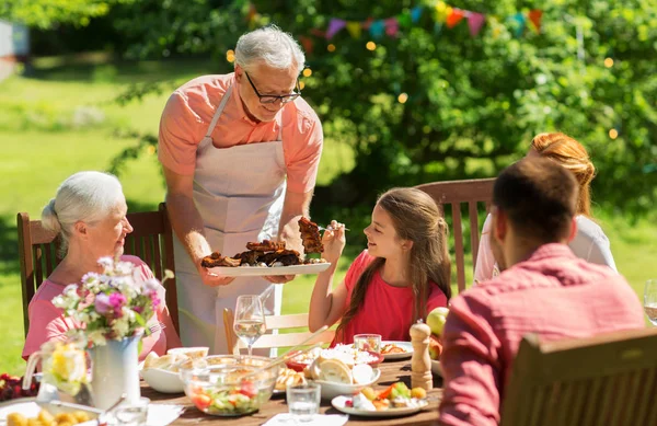 Famiglia cenare o grigliare nel giardino estivo — Foto Stock