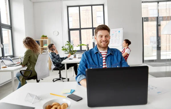Glimlachend creatieve man met laptop werken op kantoor — Stockfoto