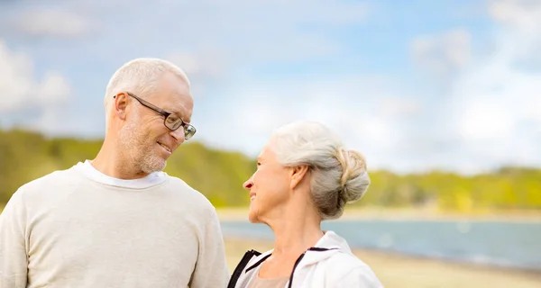 Felice coppia anziana parlando su sfondo spiaggia — Foto Stock