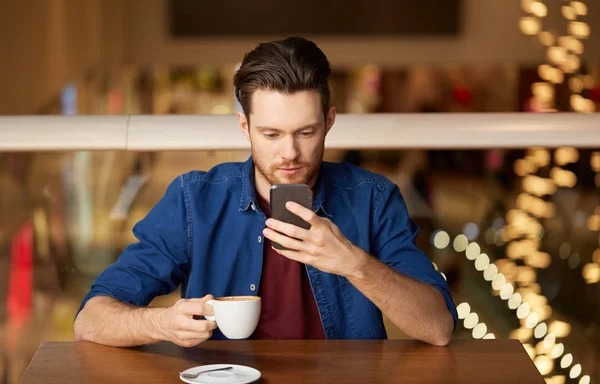 Man met koffie en smartphone bij restaurant — Stockfoto