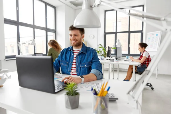 Sorrindo homem criativo com laptop trabalhando no escritório — Fotografia de Stock