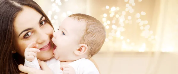 Close up of mother with baby over christmas lights — Stock Photo, Image