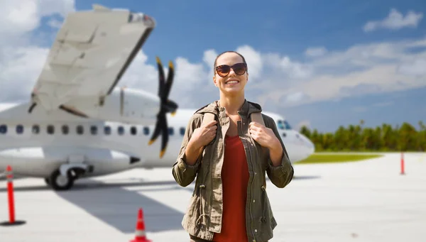 Giovane donna con zaino sopra aereo sul campo d'aviazione — Foto Stock