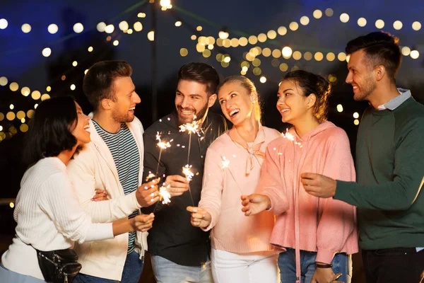 Amigos felizes com sparklers na festa no telhado — Fotografia de Stock