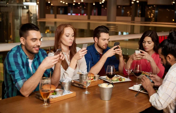 Friends with smartphones at restaurant — Stock Photo, Image