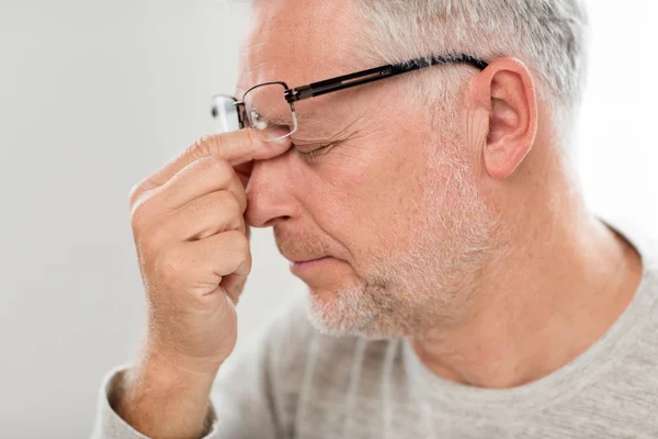 Hombre mayor en gafas masaje nariz puente — Foto de Stock