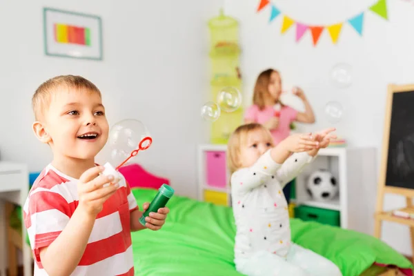 Счастливые дети, пускающие мыльные пузыри дома — стоковое фото